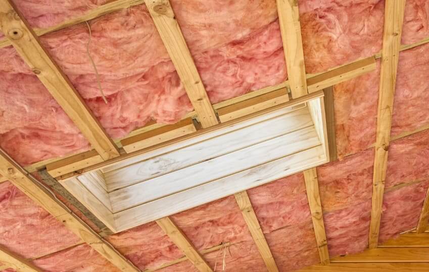 Cellulose vs Fiberglass Insulation: All You're Looking for in One Post Attic wall covered with pink fiberglass insulation in batts